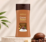 A bottle of HerbSalot Cocoa Butter Body Milk placed on a textured stone surface. The packaging is brown with a dark brown cap, showcasing cocoa butter benefits for rich hydration and antioxidant nourishment. Cocoa beans and a small block of cocoa butter are arranged beside the bottle, highlighting a natural, luxurious skincare presentation.